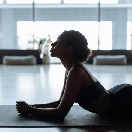 A woman in a yoga position indoors, exuding calm and relaxation on a mat.